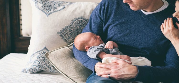 dad holding newborn on couch
